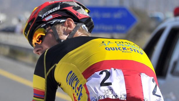 Ein Radrennfahrer mit Helm und Sonnenbrille während eines Rennens.