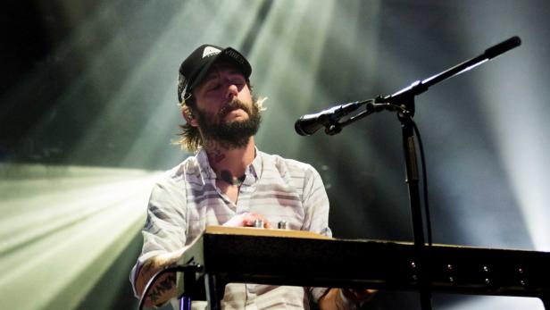 Ein bärtiger Mann mit Kappe spielt Keyboard auf einer Bühne.