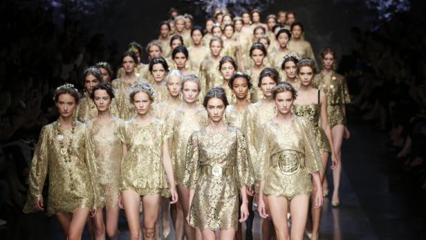 Eine Gruppe von Models in goldfarbenen Kleidern auf einer Modenschau.