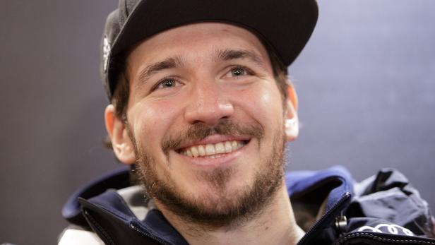 Ein lächelnder Mann mit Bart und Kappe blickt in die Kamera.