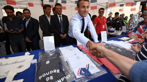 FILE PHOTO: French President Emmanuel Macron shakes hands with visitors next to items for sale as the Elysee Palace opened its doors to the public in Paris