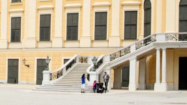 Eine Familie steht vor der Treppe eines gelben Gebäudes.