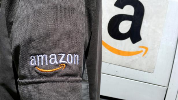 FILE PHOTO: FILE PHOTO: An Amazon.com Inc driver stands next to an Amazon delivery truck in Los Angeles, California