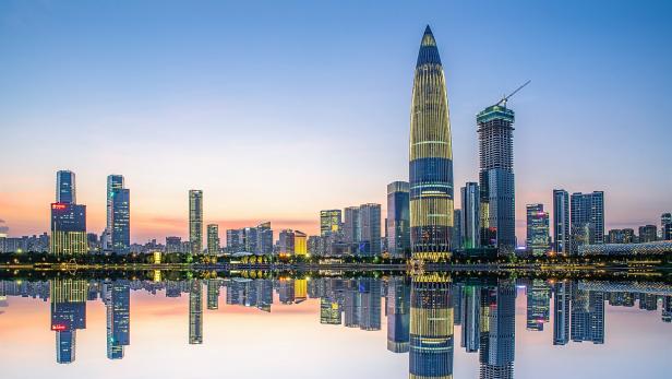 Die Skyline von Shenzhen spiegelt sich im ruhigen Wasser bei Dämmerung.
