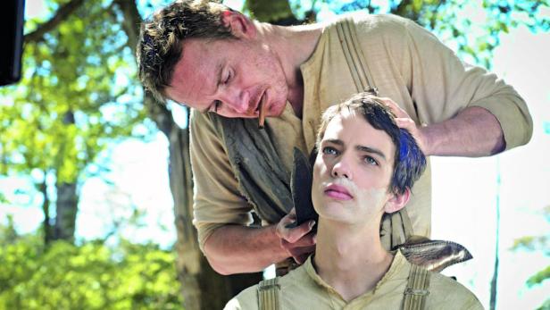 Ein Mann rasiert einem anderen Mann mit einem Messer den Bart.