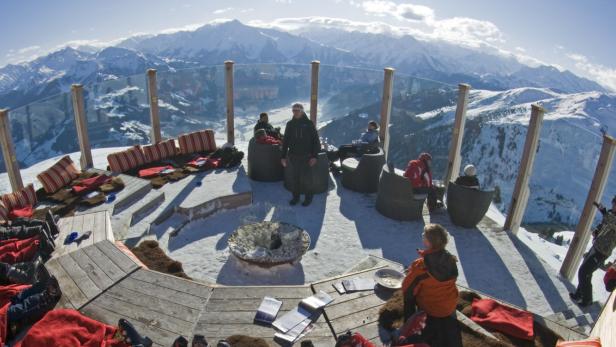 Menschen entspannen sich auf einer Terrasse mit Bergblick.