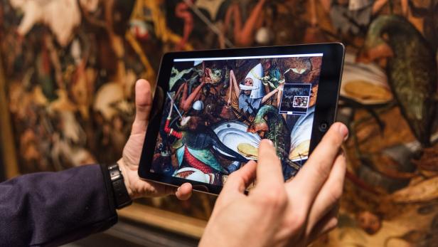 Eine Person betrachtet ein Gemälde von Hieronymus Bosch auf einem Tablet.