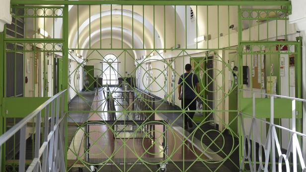 Ein Mann geht einen langen Flur mit Zellen in einem Gefängnis entlang.