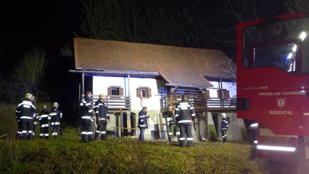 Feuerwehrleute stehen nachts vor einem Haus und einem Feuerwehrfahrzeug in Rosenthal.