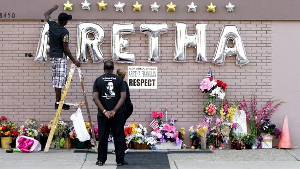A worker adjusts a balloon sign in tribute to the late singer Aretha Franklin at the New Bethel Baptist Church during a public viewing in Detroit
