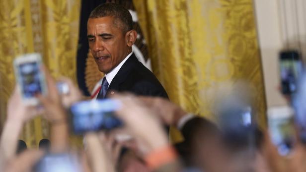 Barack Obama wird von Menschen mit Handys fotografiert.