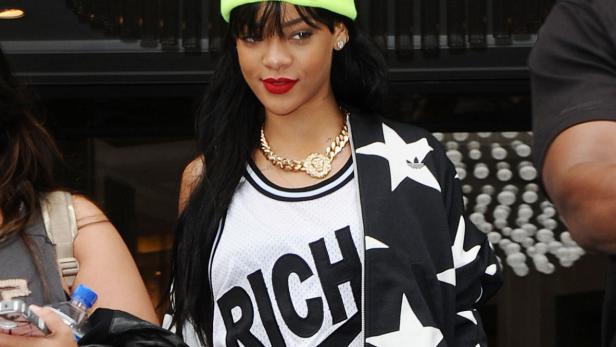 Rihanna mit neonfarbener Mütze, Goldkette und einer schwarz-weißen Adidas-Jacke mit Sternenmuster.