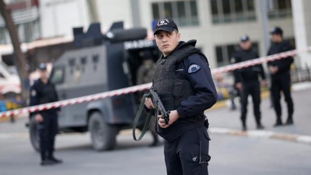 Ein türkischer Polizist mit einer Maschinenpistole steht vor einem gepanzerten Fahrzeug.