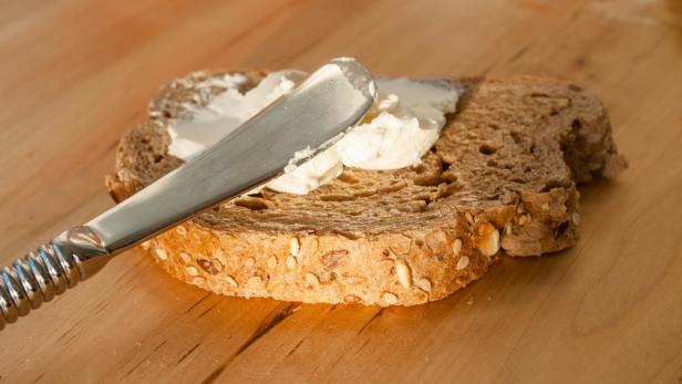 Aufstrich wird auf einer Scheibe Brot verteilt.