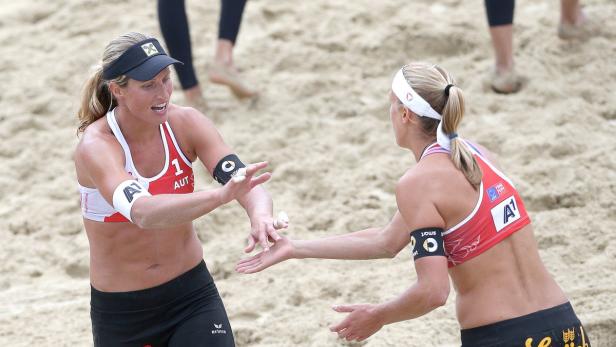 Zwei Beachvolleyballspielerinnen geben sich ein High-Five am Strand.