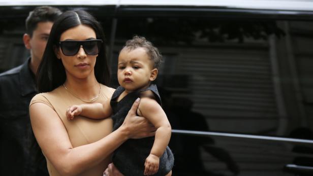 Kim Kardashian trägt ihr Kind in den Armen.
