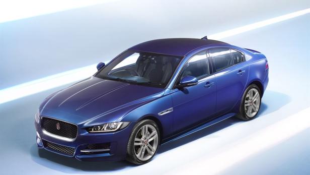Ein blauer Jaguar XE vor einem hellblauen Hintergrund.