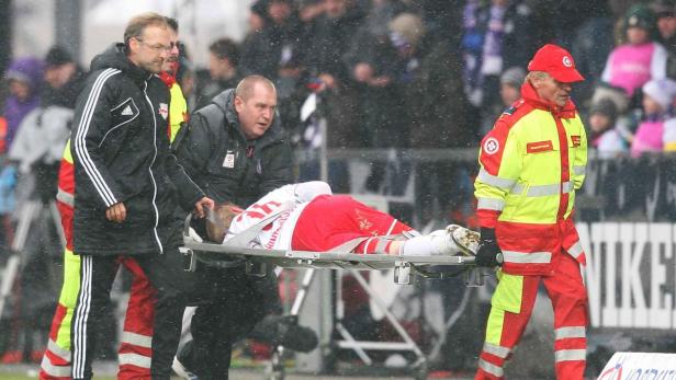 Sanitäter tragen einen verletzten Fußballspieler auf einer Trage vom Spielfeld.