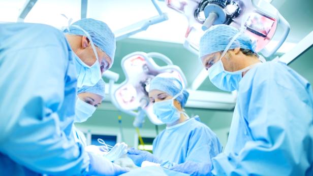 Surgeons Performing Surgery On Patient In Operating Room
