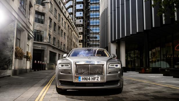 Ein grauer Rolls-Royce parkt auf einer Straße in einer Stadt.