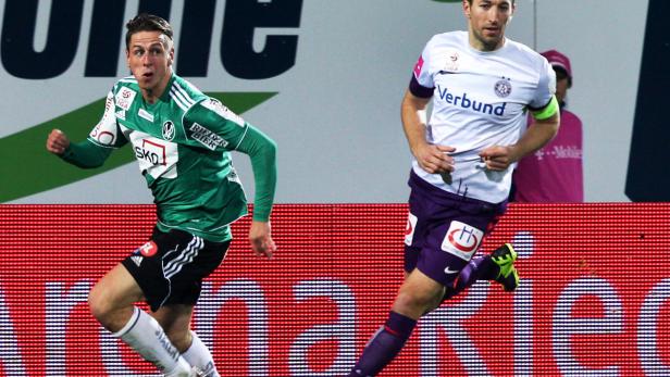 Zwei Fußballspieler kämpfen um den Ball während eines Spiels.
