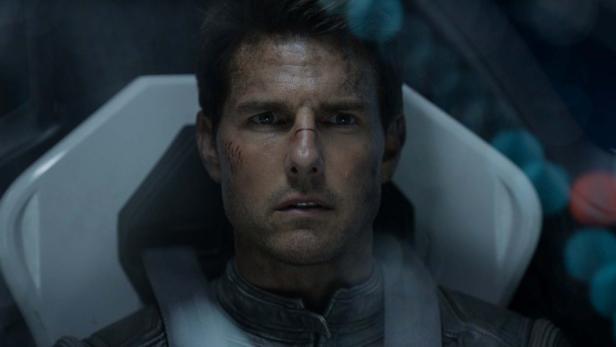 Tom Cruise mit Schrammen im Gesicht sitzt in einem Cockpit.