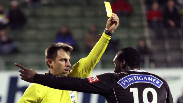 Ein Schiedsrichter zeigt einem Fußballspieler die gelbe Karte.