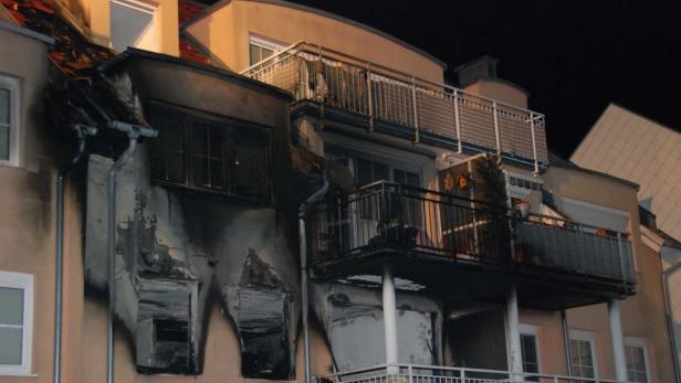 Ein Wohnhaus mit deutlichen Brandschäden an der Fassade.