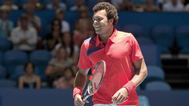 Jo-Wilfried Tsonga lächelt mit einem Tennisschläger in der Hand.