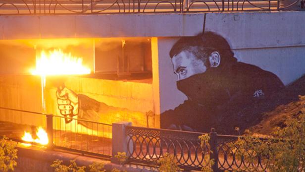 Vor einer Wandmalerei brennt ein Feuer.