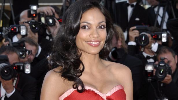 Rosario Dawson lächelt umgeben von Fotografen.