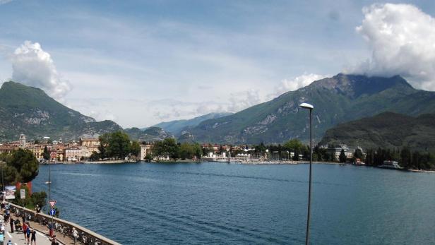 Blick über den Gardasee auf die Stadt Riva del Garda und die umliegenden Berge.