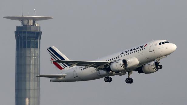 Ein Air France Flugzeug startet vor einem Kontrollturm.