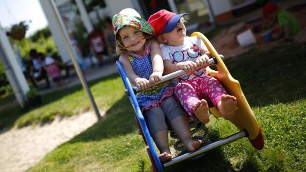 Zwei kleine Kinder haben Spaß auf einer bunten Wippe im Garten.