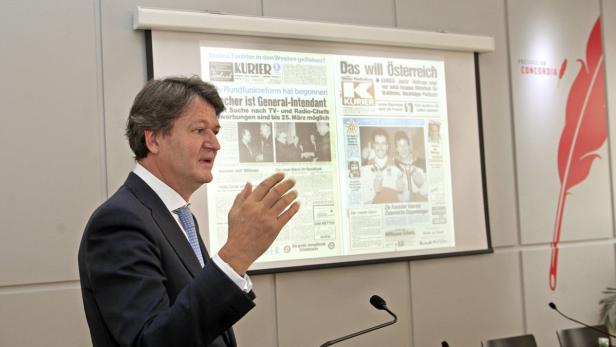 Ein Mann in Anzug präsentiert Zeitungsartikel auf einer Leinwand.