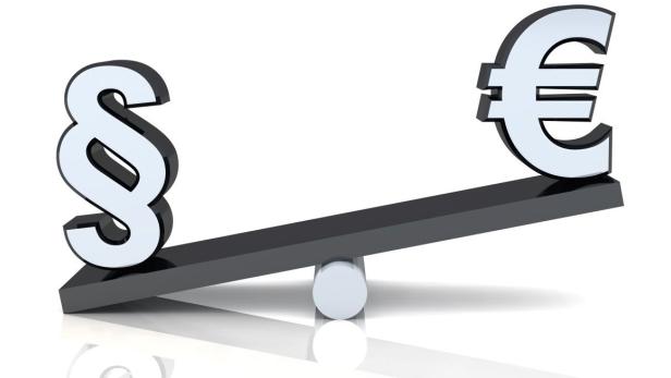 Ein Paragraph-Zeichen und ein Euro-Zeichen auf einer Wippe.