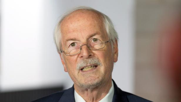 Ein älterer Mann mit Brille und grauem Haar spricht.