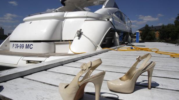 A pair of high heel shoes is placed on shore in front of a yacht during the summer contingent of the Millionaire Fair of luxury goods in Moscow, July 4, 2010. REUTERS/Sergei Karpukhin (RUSSIA - Tags: BUSINESS SOCIETY)