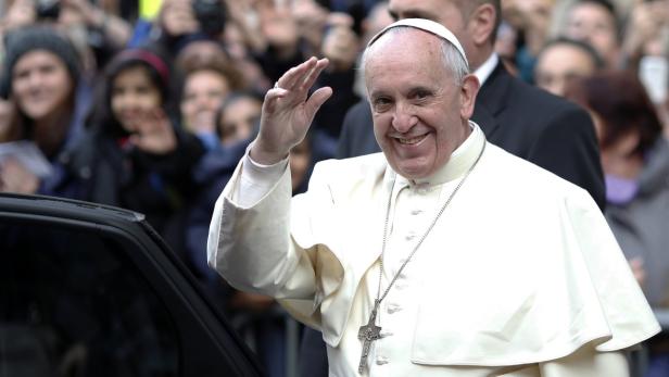 Papst Franziskus winkt lächelnd einer Menschenmenge zu.