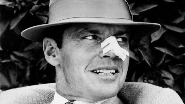 Ein Mann mit Hut und einem Pflaster auf der Nase.