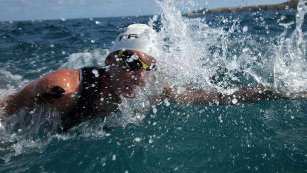 Ein Schwimmer im offenen Wasser, umgeben von Gischt.