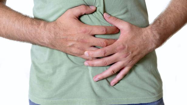 Ein Mann hält sich mit beiden Händen den Bauch.
