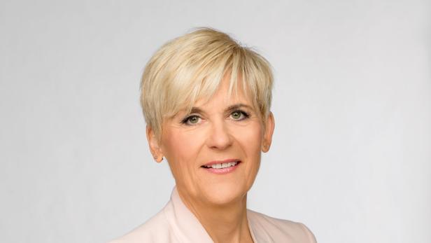 Porträt einer Frau mit blonden, kurzen Haaren und einem hellrosa Blazer.