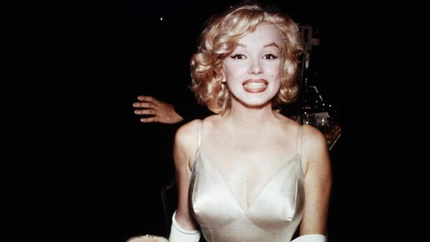 Marilyn Monroe lächelt in einem weißen Kleid.