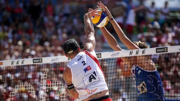 Zwei Beachvolleyballspieler kämpfen am Netz um den Ball.