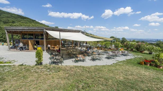 Ein Restaurant mit Außenbereich auf einem Hügel mit Blick auf die Stadt.