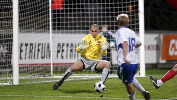 Ein Torwart in gelbem Trikot versucht, einen Fußball zu halten.