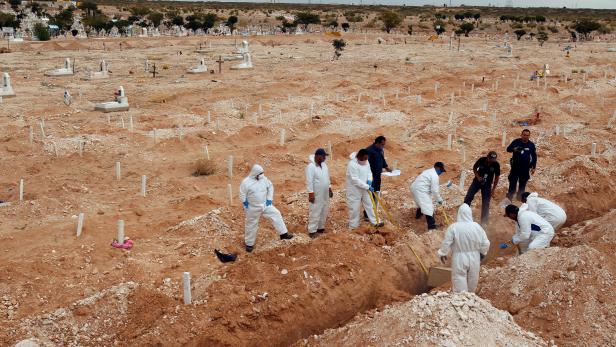 Forensic workers bury unclaimed bodies in a mass grave at San Rafael cemetery in Ciudad Juarez