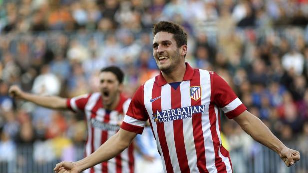 Ein jubelnder Fußballspieler im rot-weiß gestreiften Trikot von Atlético Madrid.