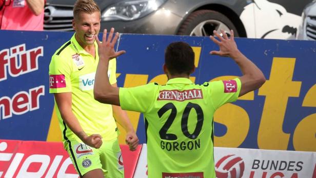 Zwei Fußballspieler in gelben Trikots feiern ein Tor.